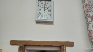 A fireplace with a clock above it, flanked by two potted plants. - Pet-Friendly Country Escape HotTub & Log Burner (Ceredigion)