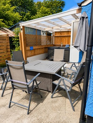An outdoor patio with a table and chairs, a covered seating area, and a wooden fence. - Synod Cottage | Private Hot Tub, Dog Friendly, Near New Quay (Ceredigion)