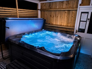 A hot tub with a wooden backdrop and a sign detailing rules and notices. - Synod Cottage | Private Hot Tub, Dog Friendly, Near New Quay (Ceredigion)