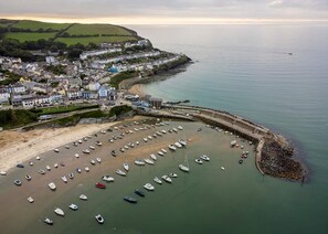 A coastal town with a marina filled with boats, a sandy beach, and residential buildings along the shore. - Synod Cottage | Private Hot Tub, Dog Friendly, Near New Quay (Ceredigion)