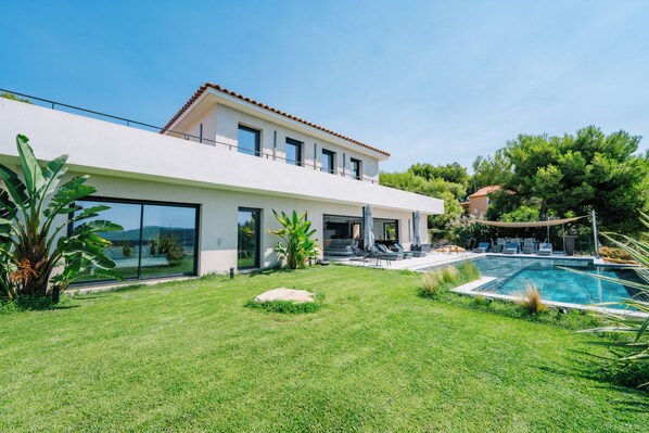 Uma casa moderna de dois andares com piscina, gramado bem cuidado e área de varanda.