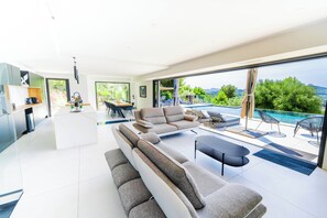 Una sala de estar moderna con un sofá, un comedor y vistas a una piscina.