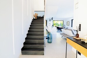 Um interior moderno com uma escada que dá acesso a uma sala de jantar e uma sala de estar.