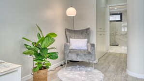 A modern interior with a grey upholstered chair, a potted plant, a white furry rug, and a floor lamp. - Tristão Vaz I, a Home in Madeira (Machico)