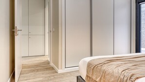 A bedroom with a bed, a wardrobe, and a door leading to another room. - Tristão Vaz I, a Home in Madeira (Machico)