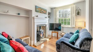 Un salon chaleureux avec une cheminée, un téléviseur et des fauteuils confortables.