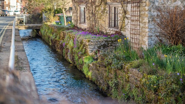 Un bâtiment en pierre avec un étroit canal d’eau devant.