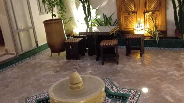 Een binnenplaats met een fontein, een zitgedeelte en potplanten.