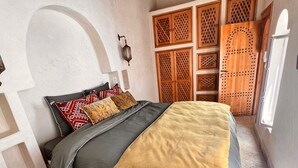 Een slaapkamer met een bed, een houten garderobe en een hangende lamp.