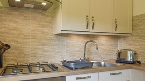 A modern kitchen with a gas stove, oven, stainless steel sink, and a toaster. - 1 bedroom accommodation in Lostwithiel (Lostwithiel)