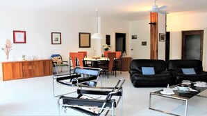 En moderne stue med spiseplads, med sofa, stole, sofabord og spisebord.