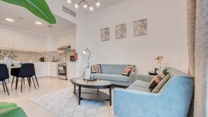 En moderne stue med en lyseblå sofa, et rundt sofabord og et spiseområde med stole.