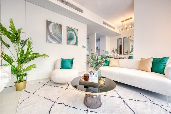 A modern living room with a white sofa, a round coffee table, and two abstract paintings on the wall.