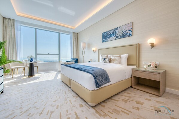 A modern hotel room with a large bed, a desk, and a view of the city.