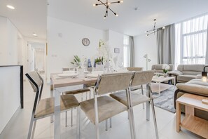 Uma sala de estar moderna com um sofá, uma mesa de jantar com cadeiras e um candelabro.