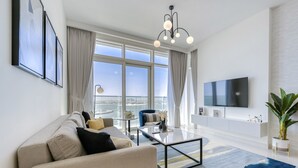 A modern living room with a sofa, coffee table, and a TV mounted on the wall. - Idyllic 1BR at Sunrise Bay Tower 1 Emaar Beachfront Dubai Marina by Deluxe Holiday Homes (Dubai)
