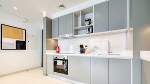 A modern kitchen with grey cabinets, a built-in oven, and a coffee maker on the countertop. - Idyllic 1BR at Sunrise Bay Tower 1 Emaar Beachfront Dubai Marina by Deluxe Holiday Homes (Dubai)