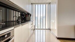 Una cucina moderna con un piano di lavoro nero, elettrodomestici in acciaio inossidabile e vista su alti edifici tramite un'ampia finestra.