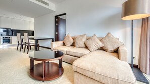 Un soggiorno moderno con un divano angolare beige, un tavolino rotondo e un'area pranzo con un tavolo e sedie scuri.