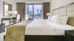 Een hotelkamer met een groot bed, een bureau, een stoel en uitzicht op de stadsgezicht door het raam.