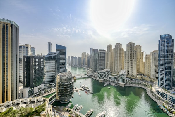 A high-rise urban area with modern skyscrapers, a marina with boats, and a river.