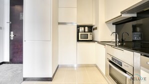 Een moderne keuken met witte kastjes, een magnetron, een fornuis en een zwart aanrecht.