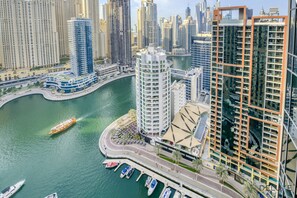 Ein Hochhaus mit gebogener Fassade, eine Marina mit Booten und eine Stadtlandschaft im Hintergrund.