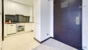 Una cocina moderna con armarios blancos, un horno empotrado y una puerta de madera oscura con una placa.
