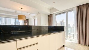 A modern kitchen with a black countertop, white cabinets, and a large window with curtains. - Pristine 3BR at The Address Residences Dubai Marina by Deluxe Holiday Homes (Dubai)