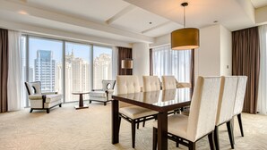 A hotel room with a large dining table, multiple chairs, a sofa, and a view of city buildings through large windows. - Pristine 3BR at The Address Residences Dubai Marina by Deluxe Holiday Homes (Dubai)