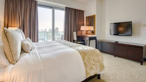 A hotel room with a large bed, a desk, a television, and a view of the city. - Pristine 3BR at The Address Residences Dubai Marina by Deluxe Holiday Homes (Dubai)