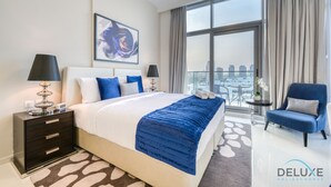 Une chambre d’hôtel moderne avec un grand lit, une table de chevet, une chaise, un balcon avec vue sur la ville et un tableau au mur.
