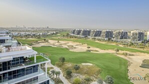 Un hôtel moderne à plusieurs étages, doté d’un parcours de golf et offrant une vue sur les gratte-ciel de la ville en arrière-plan.