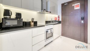 Une cuisine moderne avec des armoires blanches, un comptoir noir, un four à micro-ondes, un grille-pain, une cuisinière et un extincteur.