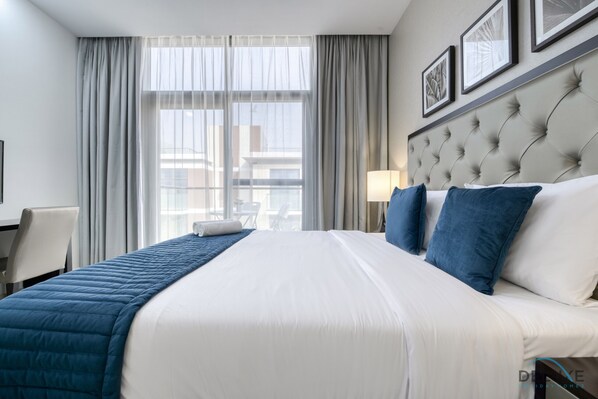 A hotel room with a large bed, a desk, and a chair.