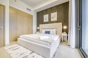 A modern bedroom with a large bed, wooden wardrobe, and two wall-mounted artworks.