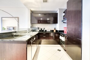 Uma cozinha moderna com armários de madeira escura, eletrodomésticos de aço inoxidável e painel de azulejos.