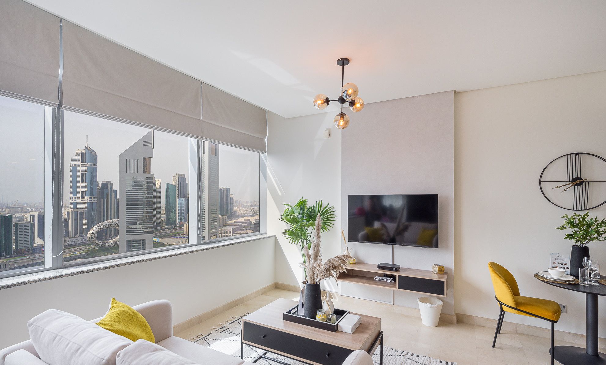Ein modernes Wohnzimmer mit Blick auf die Stadt, einem Flachbildfernseher und einer Essecke mit einem gelben Stuhl.