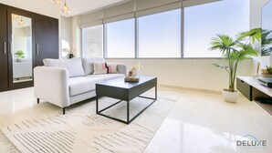 Una sala de estar moderna con un sofá, una mesa de centro y ventanas amplias.