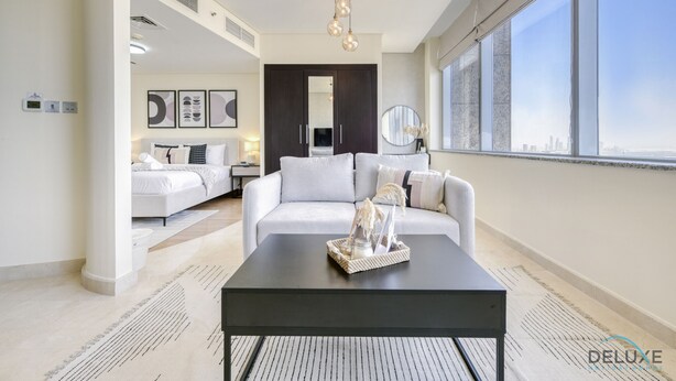 Un salón moderno con una mesa de centro negra, un sofá blanco y un ventanal con vistas a la ciudad.