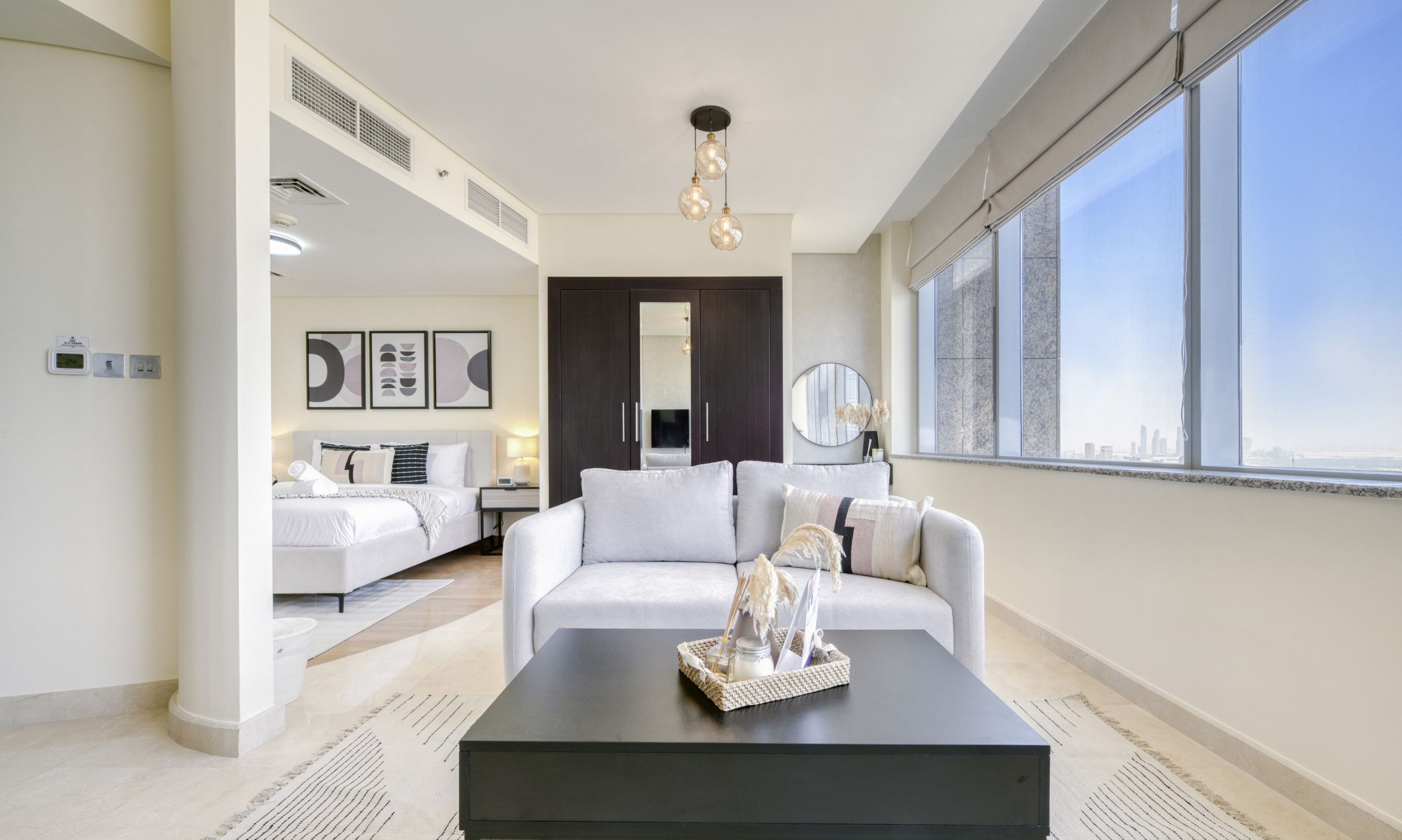 Ein modernes Wohnzimmer mit einem schwarzen Couchtisch, einem weißen Sofa und einem großen Fenster mit Blick auf die Stadt.
