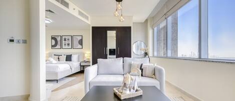 Ein modernes Wohnzimmer mit einem schwarzen Couchtisch, einem weißen Sofa und einem großen Fenster mit Blick auf die Stadt.