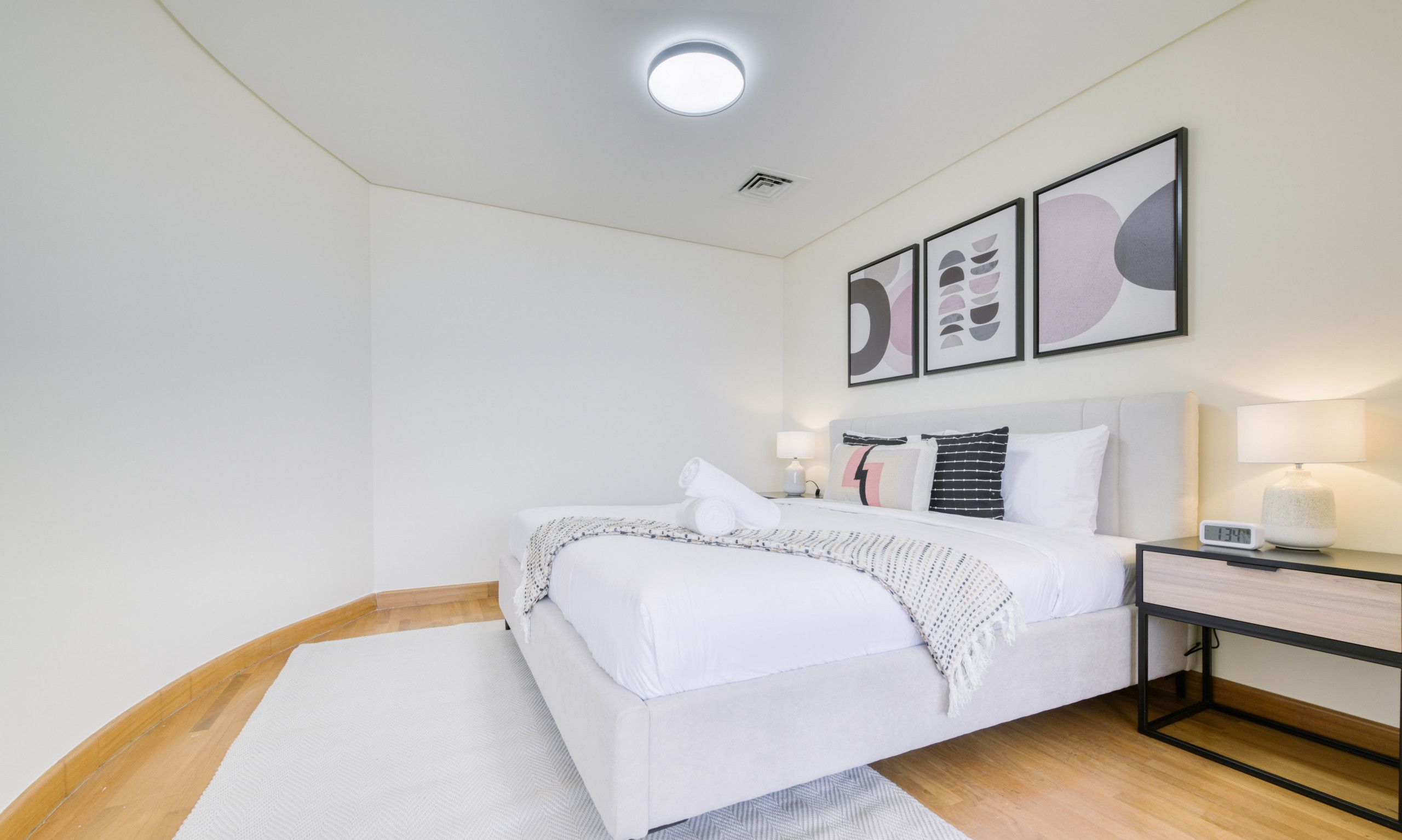 Ein modernes Schlafzimmer mit Bett, Nachttischen und abstrakter Wandkunst.