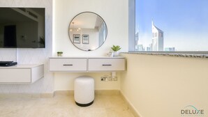 Un baño moderno con un espejo grande, una planta pequeña y vistas a un horizonte urbano a través de una ventana.