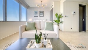 Una sala de estar moderna con un sofá, una mesa de centro con objetos decorativos y un ventanal grande.