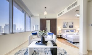 Una habitación de hotel moderna con un ventanal grande, un sofá, una cama y una zona de comedor.