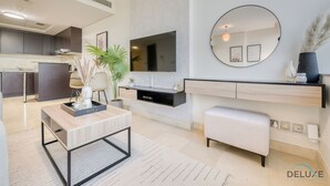 Un soggiorno moderno con una TV a schermo piatto, uno specchio rotondo, un tavolino da caffè e un design minimalista.