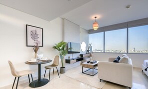 A modern living room with a dining area, a flat-screen TV, and a large window with a city view. - Opulent Studio at Sky Gardens DIFC by Deluxe Holiday Homes (Dubai)