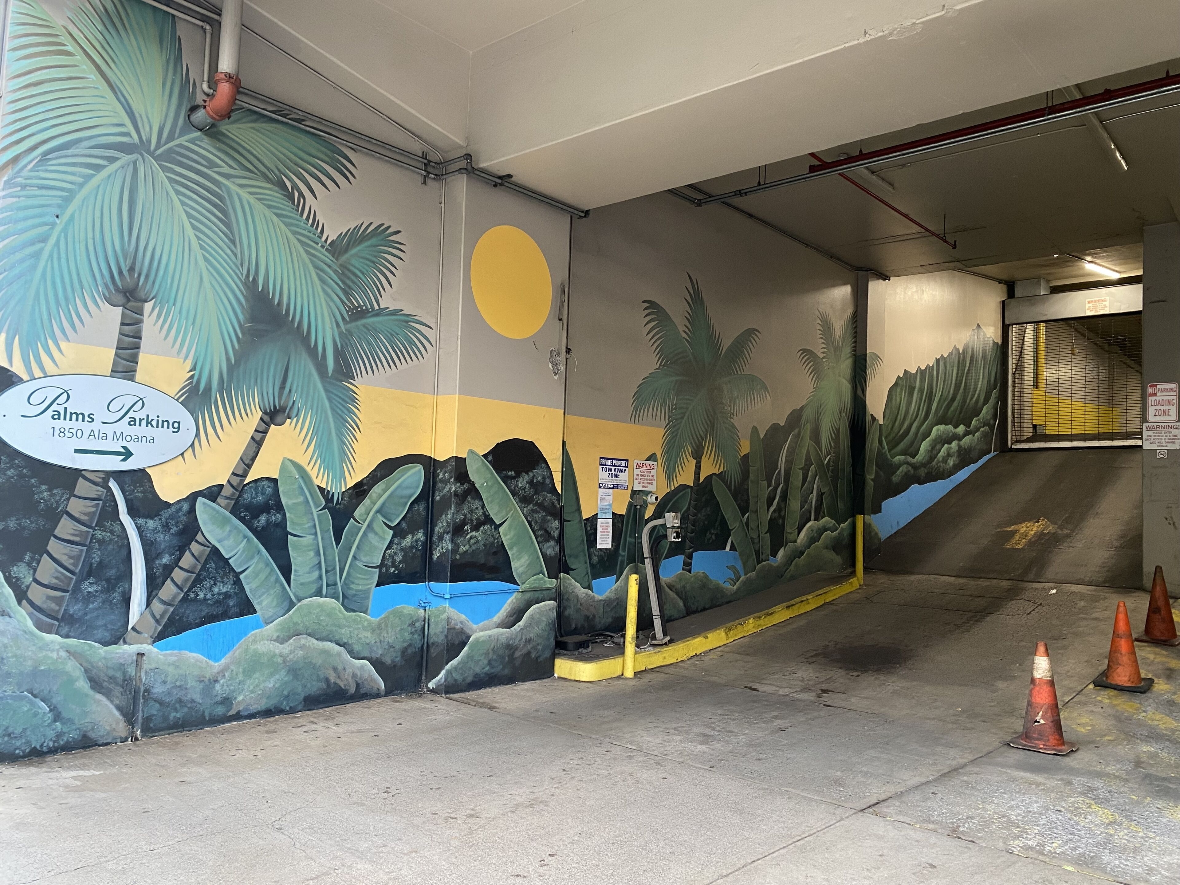 A parking garage with a mural of palm trees and a sun, and a sign indicating 'Palms Parking 1850 Ala Moana.'
