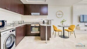 Una cocina moderna con armarios de madera oscura, horno empotrado y encimera de granito. Cuenta con un comedor con una mesa redonda y sillas amarillas.